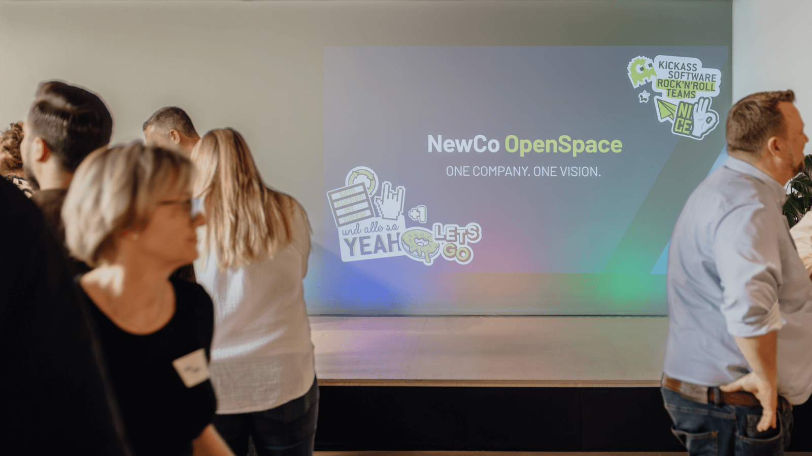#5havebecome1: Seibert Solutions takes flight for your Atlassian ecosystem! - photo of people in front of our event stage with "NewCo OpenSpace - one company, one vision" projected onto the background