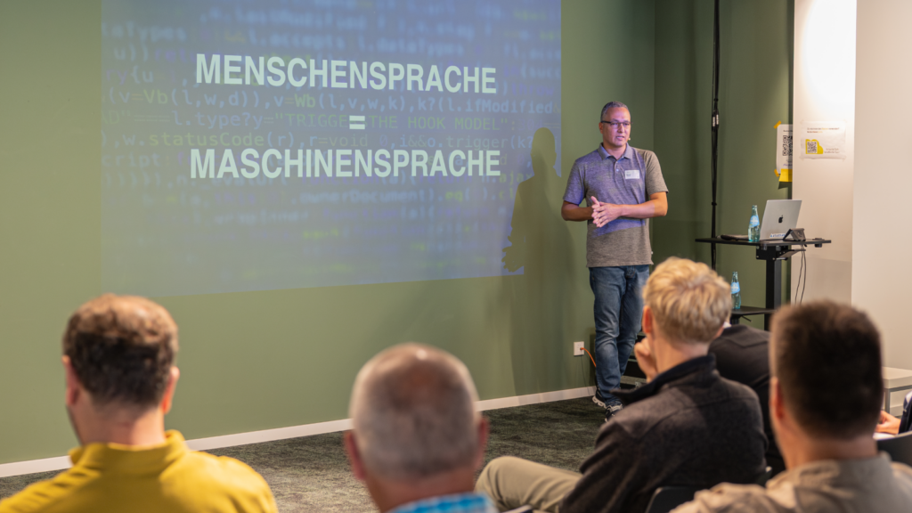 Dennis Hauck steht vor einer Leinwand und hält einen Vortrag zum Thema AI beim ITSM Open Space