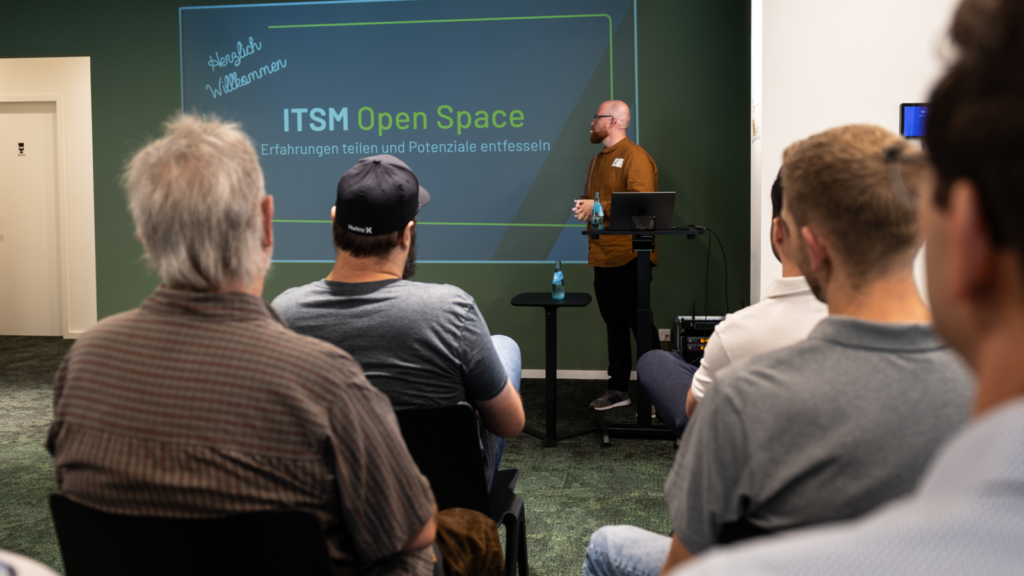 Kai Becker steht vor einer Leinwand und eröffnet den 1. ITSM Open Space bei Seibert Media